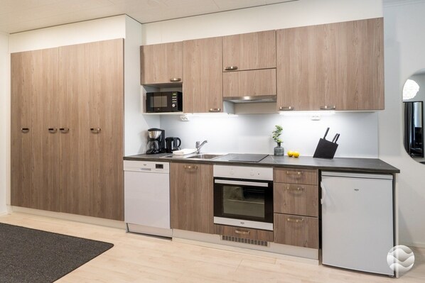 A modern kitchen with wooden cabinets, a built-in microwave, a coffee maker, and a refrigerator.