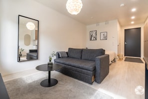 A modern living room with a grey sofa, a round coffee table, and a large mirror on the wall.
