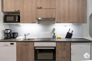 A modern kitchen with wooden cabinets, a built-in microwave, a coffee maker, and a dishwasher.