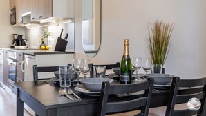 A modern kitchen with a dining table set for two, a bottle of champagne, and a mirror on the wall. - Meriheinä B7 by Holiday in Kalajoki (Kalajoki)