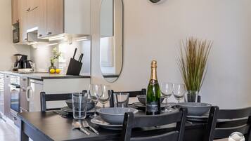 A modern kitchen with a dining table set for two, a bottle of champagne, and a mirror on the wall.