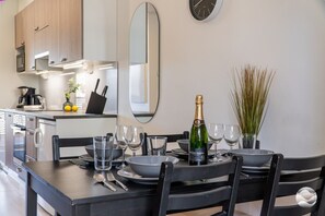 Cozinha moderna com mesa de jantar posta para dois, uma garrafa de champanhe e um espelho na parede.