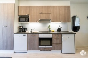 A modern kitchen with wooden cabinets, a microwave, a coffee maker, a sink, and a stove.