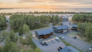 An aerial view of a building complex with multiple structures, parking area, and surrounding forested landscape. - Meriheinä B7 by Holiday in Kalajoki (Kalajoki)