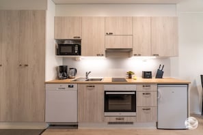A compact kitchen with a microwave, coffee maker, and a small refrigerator.