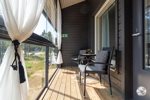A balcony with a table and chairs, a view of the outdoors, and a door with a sign.