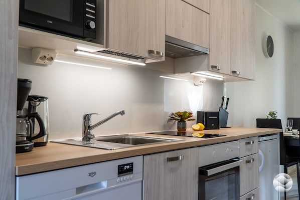 A modern kitchen with a built-in dishwasher, stainless steel appliances, and a microwave.