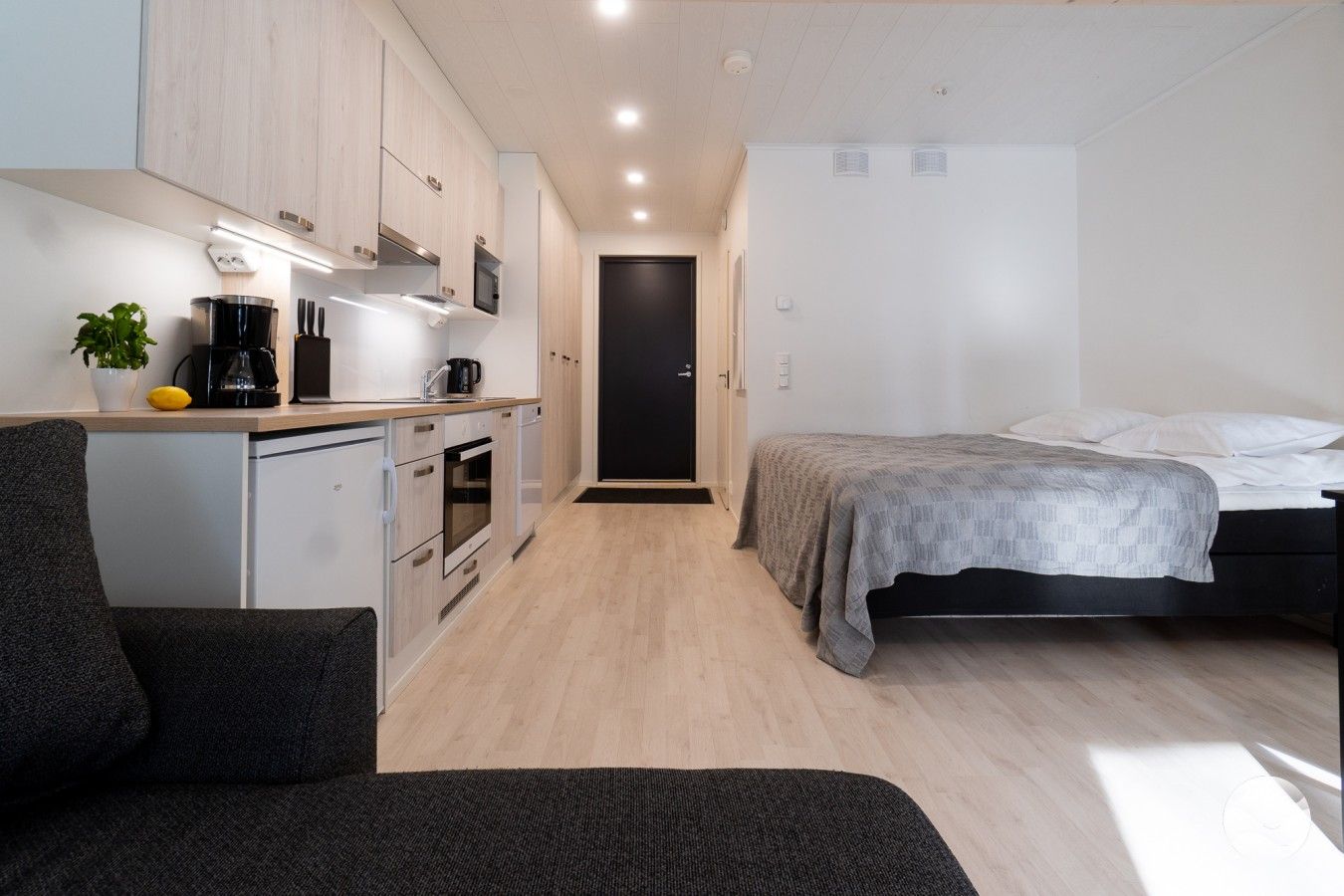Una habitación funcional con kitchenette, cama y una pequeña zona de estar.