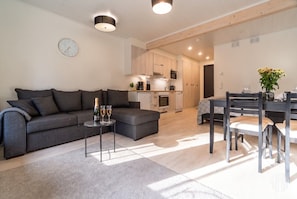 A modern living room with a sofa, coffee table, and dining area with chairs.