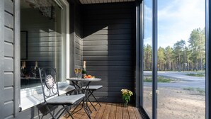 En træterrasse med et bord og stole, en champagneflaske og en vase med blomster.