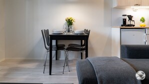 Cozinha moderna com área de jantar, incluindo uma mesa posta para dois, cadeiras, um relógio e uma luminária pendente.