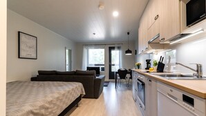 Um apartamento moderno com cama, sofá, cozinha compacta e área de refeições.