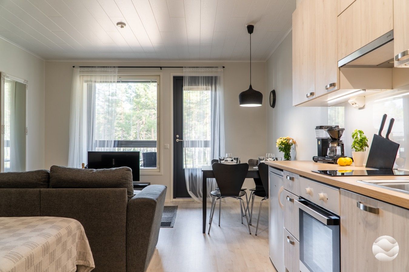 Moderni keittiö, jossa on ruokailutila, sohva ja televisio.