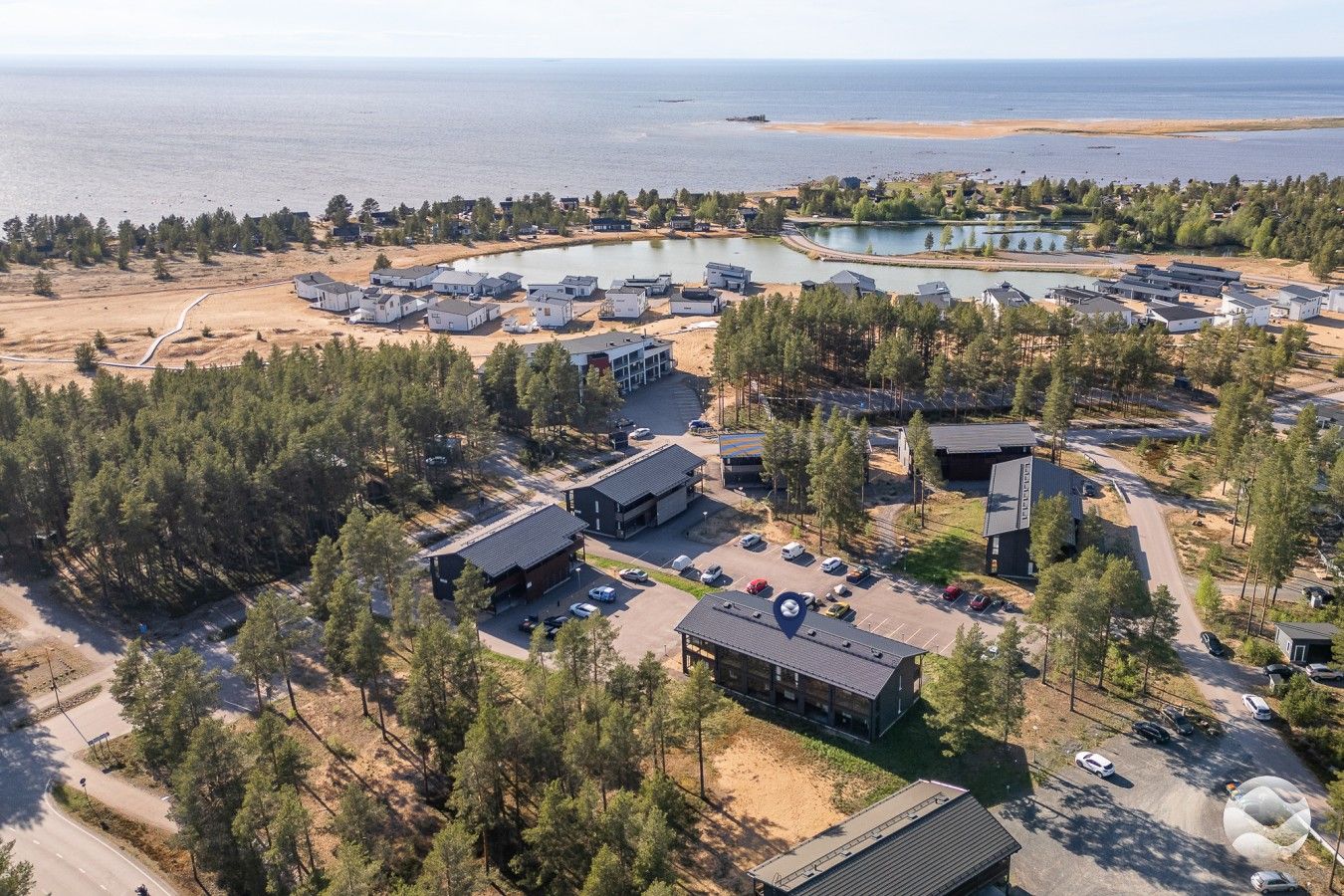 Ilmakuva asuinalueesta, jossa näkyy taloja, parkkipaikka ja vesialue.