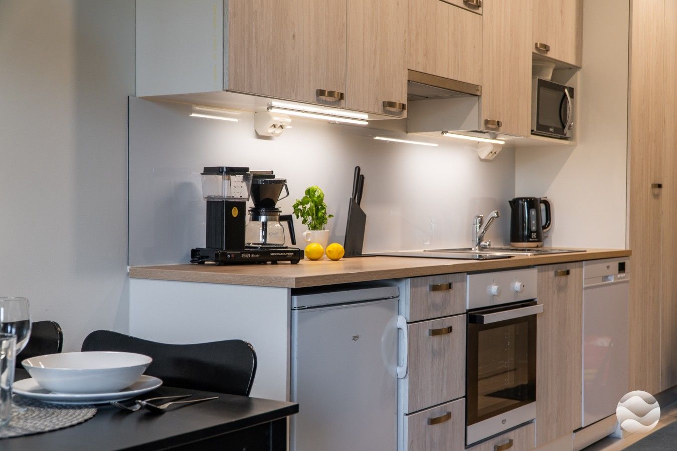 A modern kitchen with a coffee machine, sink, and cabinets.
