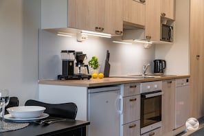 A modern kitchen with a coffee machine, sink, and cabinets.