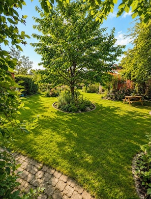 A well-maintained garden with a central tree, a stone pathway, and a wooden bench.