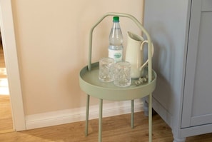 A light green metal chair with a white pitcher and two clear glasses on a tray.