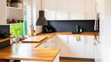 A modern kitchen with white cabinets, a wooden countertop, and a black pendant light.
