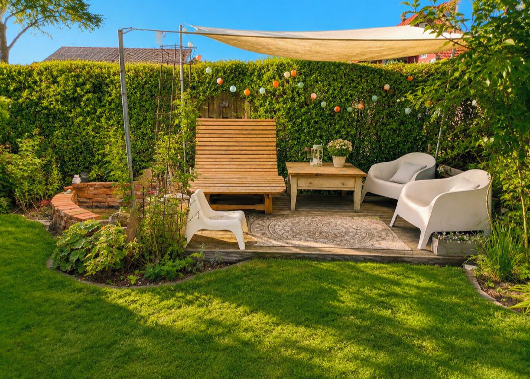 Eine Terrasse mit einem Holztisch, zwei weißen Stühlen und einem kleinen Tisch.