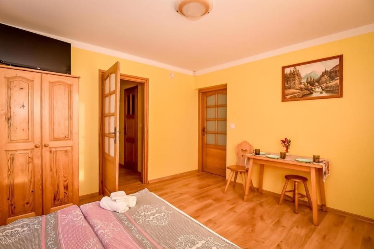 A room with a bed, a desk, a chair, and a wardrobe.