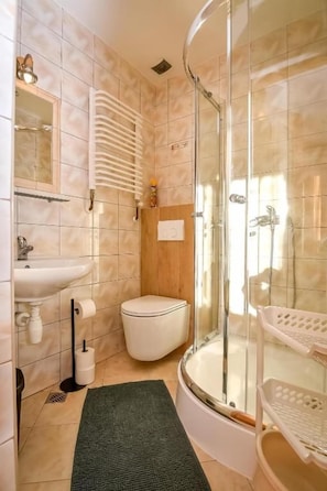 A bathroom with a glass shower enclosure, a sink, a toilet, and a green rug. - Willa Piękne Widoki (Ząb)