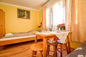 A room with a bed, a table with stools, a window with curtains, and a painting on the wall. - Willa Piękne Widoki (Ząb)
