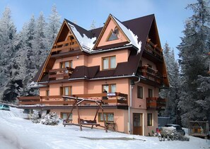 A multi-story chalet with a ski lift in the foreground, surrounded by snow-covered trees. - Willa Piękne Widoki (Poronin)