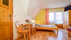 Una habitación con cama, muebles de madera, una ventana con cortinas y una puerta.