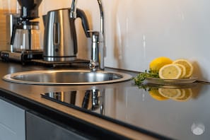 A kitchen with a stainless steel sink, a coffee maker, and lemon slices on the counter. - Polar Charm H Holiday in Lapland (Ylläs)