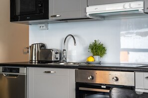 Eine moderne Küche mit Edelstahlgeräten, einem eingebauten Backofen und einem Fenster über der Spüle.