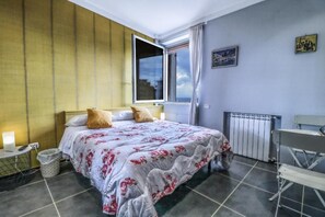 Quarto de hotel com cama, janela, radiador e uma cadeira.