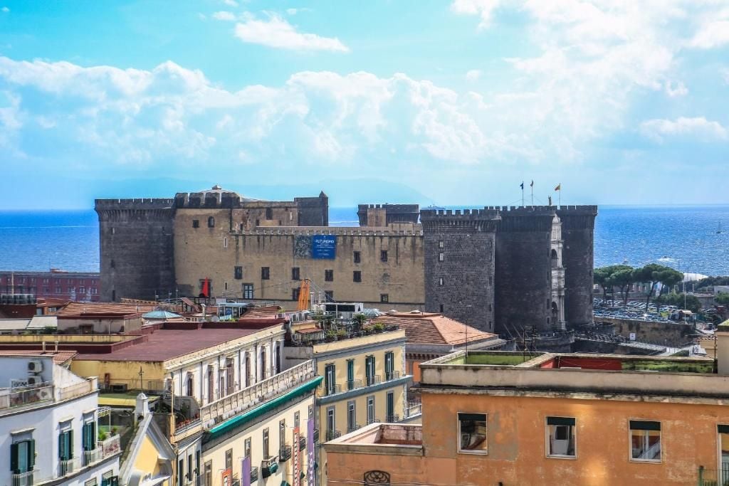 Un château historique doté de nombreuses tours, situé dans une ville côtière, avec des bâtiments en premier plan.