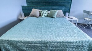 A bed with a textured green bedspread, a wooden headboard, and several pillows. - IL GRATTACIELO B&B (Napoli)