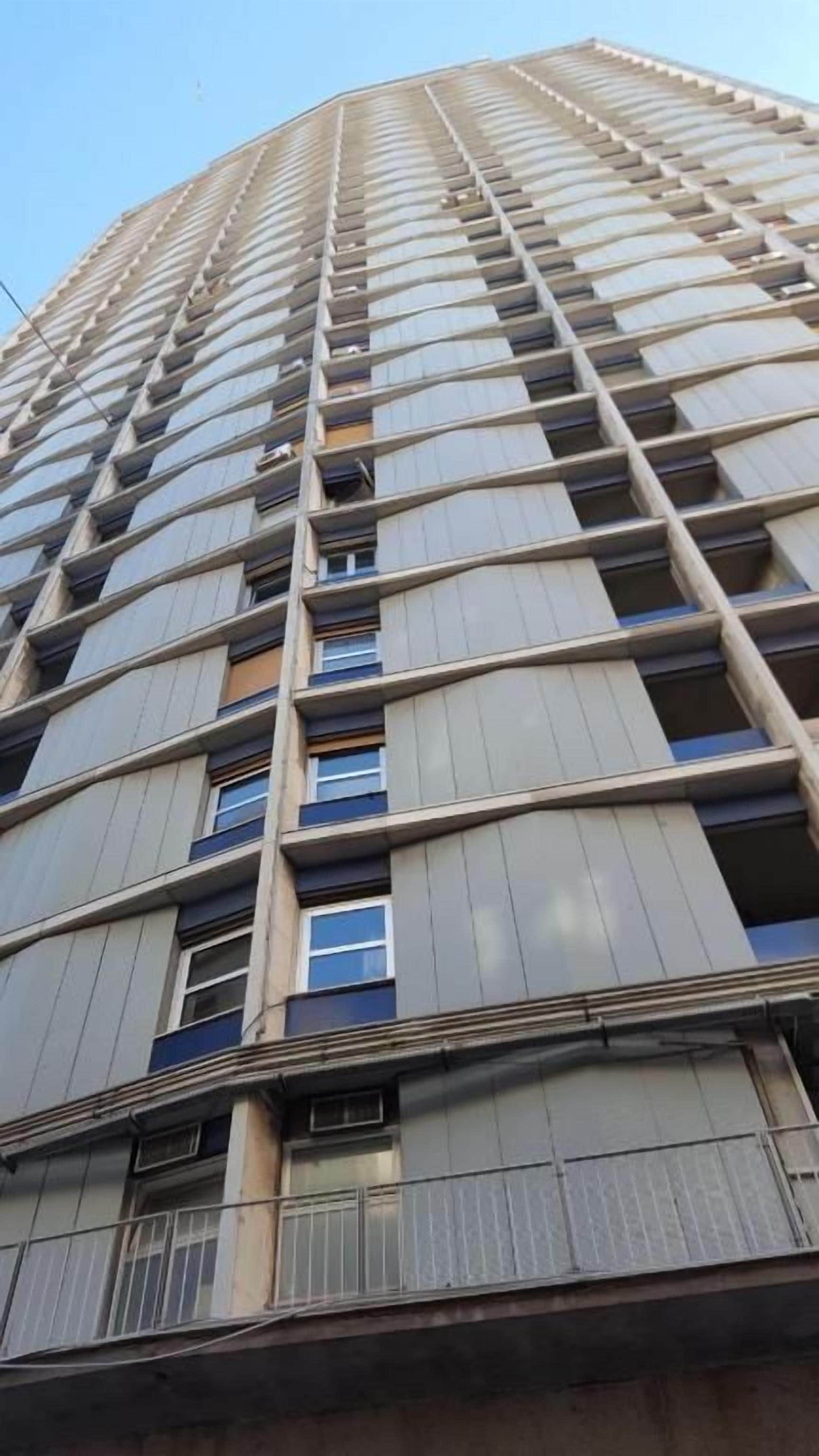 Un immeuble de grande hauteur, doté de nombreux étages, de grandes fenêtres et de balcons.