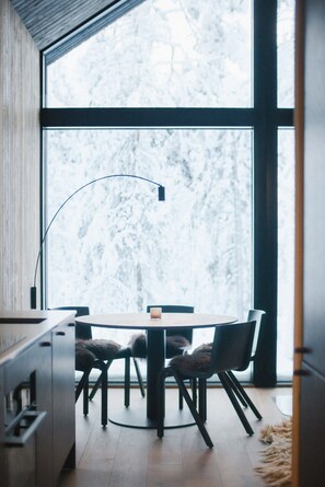 A modern dining area with a round table, two chairs, and a floor lamp.