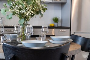 A dining table set with white plates, clear glasses, and a vase with white flowers. - Polar Charm C by Holiday in Lapland (Ylläs)