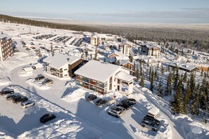A snow-covered resort with multiple buildings, parking lots, and a clear view of the surrounding forest. - Polar Charm C by Holiday in Lapland (Ylläs)