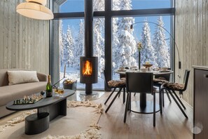 Ein gemütliches Wohnzimmer mit Kamin, einem Essbereich mit Tisch und Stühlen sowie einer Couch und einem Schachbrett.