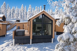 A cabin with a large glass window, wooden exterior, and a deck area.