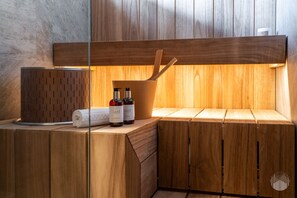 Un sauna en bois avec un banc, un seau en bois et deux bouteilles de lotion.