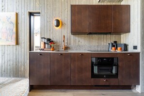 A modern kitchen with wooden cabinets, a built-in oven, and a coffee machine.