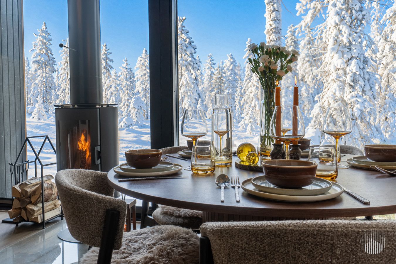 Un coin repas chaleureux avec une cheminée, des meubles en bois et une vue sur des arbres couverts de neige.