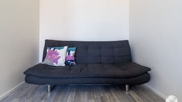 A dark-colored sofa with metal legs, two decorative pillows, and a wooden floor.