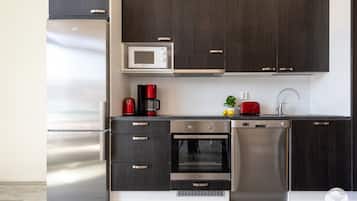 Een moderne keuken met donkere houten kastjes, roestvrijstalen apparatuur en een compacte indeling.