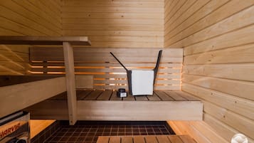 Una sauna con bancos de madera y un calentador pequeño.