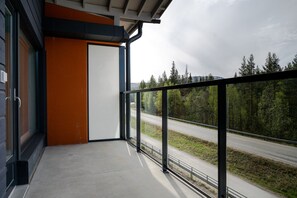 A balcony with a metal railing overlooking a road and forest. - Äkäsentie 1 A 309 by Holiday in Lapland (Äkäslompolo)
