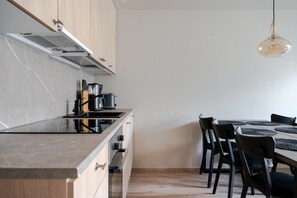 Une cuisine moderne dotée d’un îlot central, d’une table à manger avec des chaises et d’un luminaire suspendu.