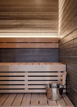 A sauna with wooden benches and a metal bucket. - Äkäsentie 1 A 102 by Holiday in Lapland (Äkäslompolo)