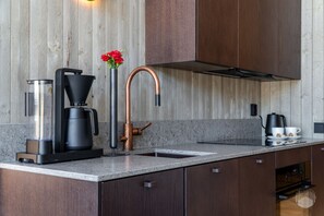 A modern kitchen with a coffee maker, a copper faucet, and a vase with flowers. - North Suite Sky by Holiday in Lapland (Levi)